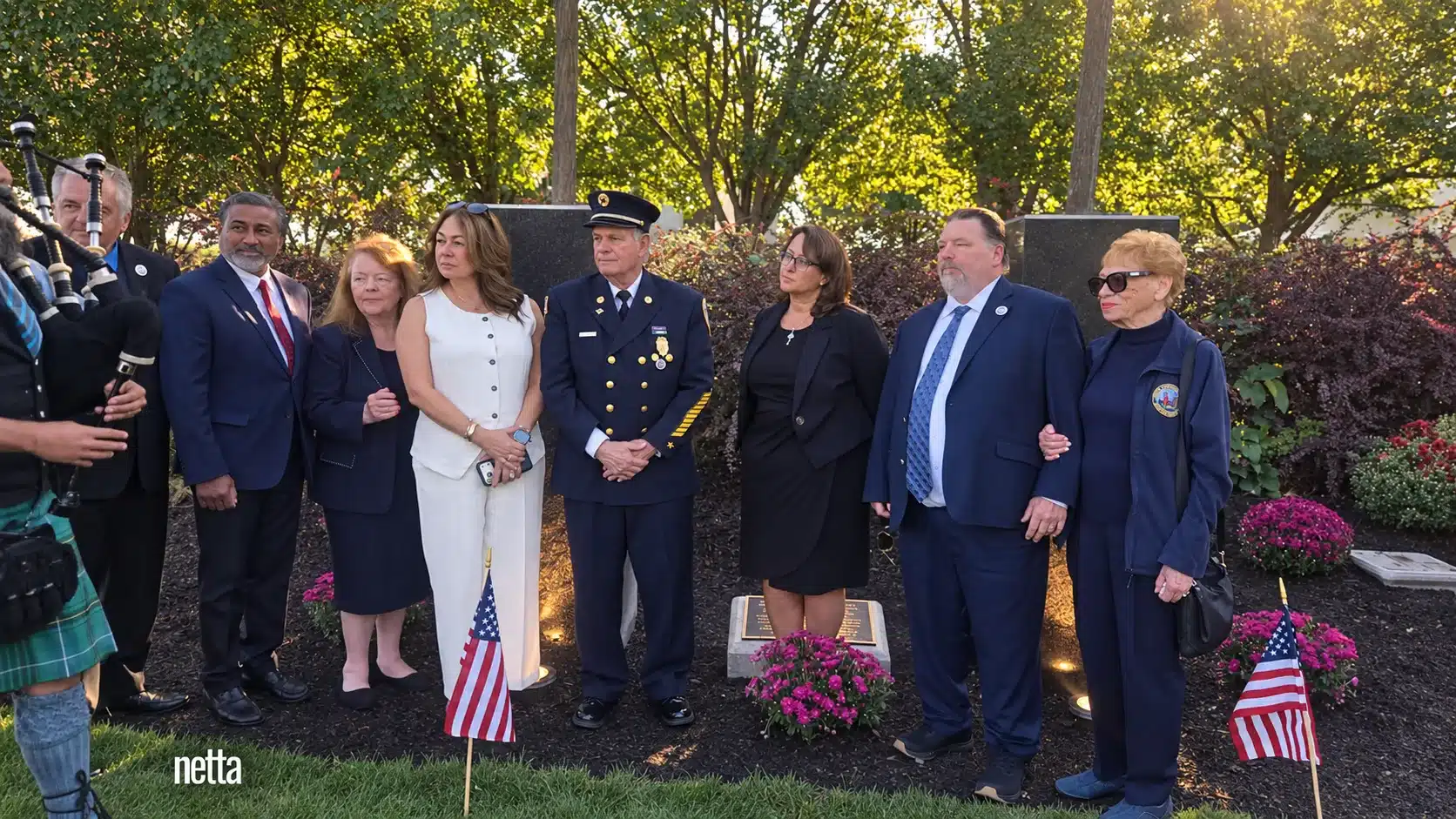 Attendees gathered beside the Bergen County 9/11 Memorial, with American flags and flowers.
